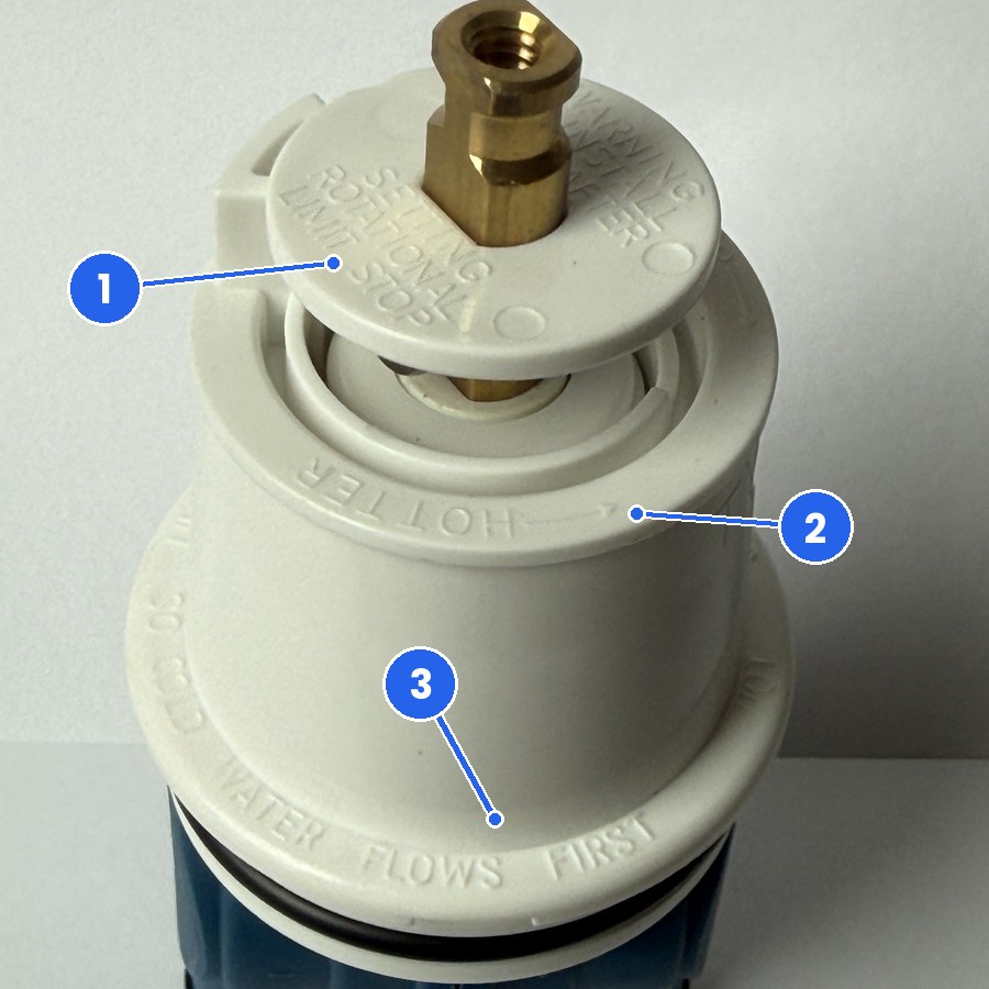 Rotational limit stop markings on a Delta Monitor 1300/1400 replacement cartridge Close view of the cap of the FourHome replacement for Delta RP19804 showing the disc marked SETTING ROTATIONAL LIMIT STOP, the molded word HOTTER with an arrow, and the rim note that cold water flows first