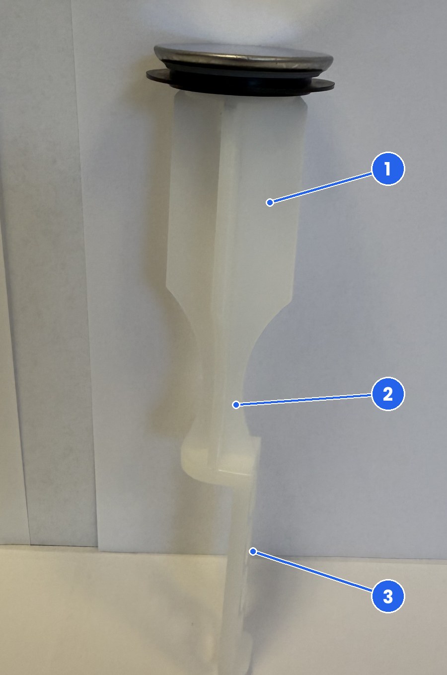 Real photo of the FourHome pop-up sink stopper seen from the side, showing the narrow neck below the body and the thin hole strip at the foot, each marked with a number