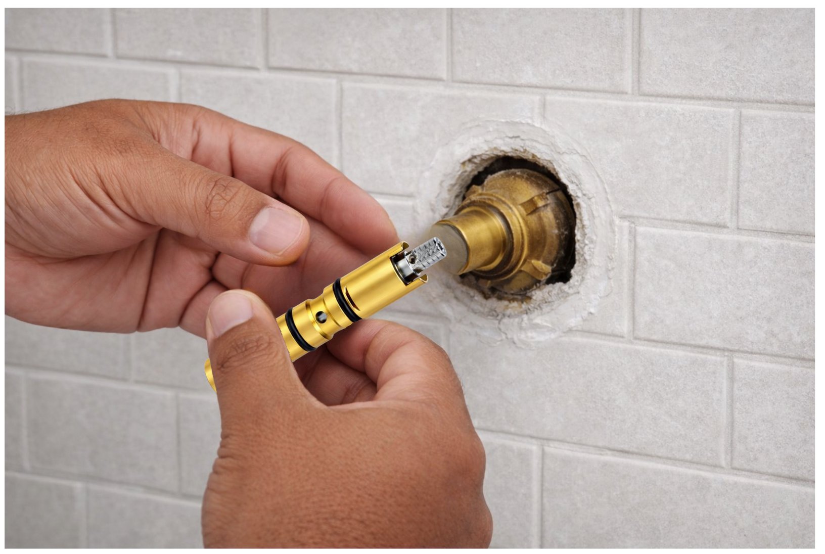 Hands installing a brass faucet cartridge into a shower valve body through white tile
